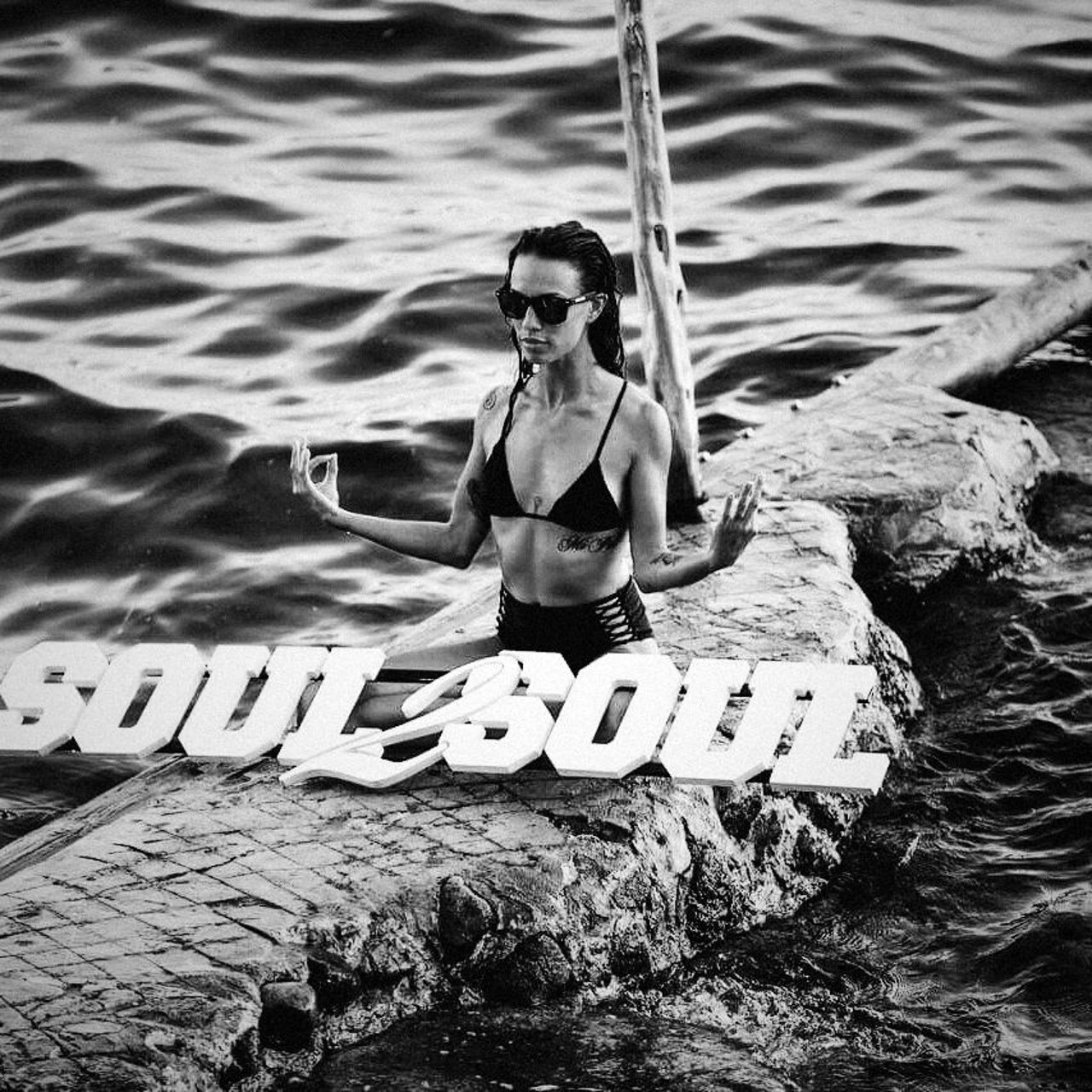 Gast auf einem Felsen am Meer vor Ibiza, davor der Soul2Soul-Schriftzug