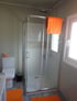 Modernes Badezimmer mit weißer Toilette, Duschkabine und orangefarbenen Badematten in der Villa Aperol.