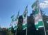 Vier weiß-grüne Fahnen mit dem Aufdruck Küchenstudio wehen vor grünen Bäumen unter blauem Himmel.