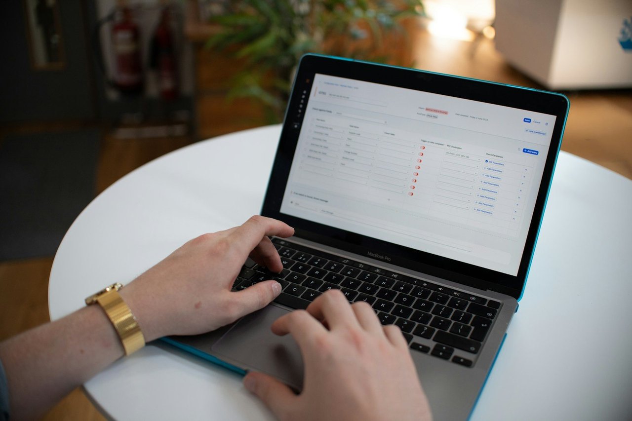 Hände tippen auf einem Laptop, auf dem Bildschirm eine Tabelle