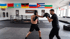 Zwei Männer boxen im Ring; einer trägt einen Helm und boxt gegen den Trainer.