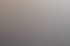 Eine lächelnde Frau mit Brille und orangefarbener Bluse sitzt an einem Tisch und hält einen Stift.