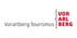 Logo von Vorarlberg Tourismus mit schwarzem Text "Vorarlberg Tourismus" und rotem Text "VOR ARL BERG" vertikal.