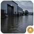 Überschwemmtes Industriegebiet mit einer Lagerhalle und einem Bürogebäude bei trübem Wetter und Hochwasser - Software für Alarm- und Gefahrenabwehrplanung - Notfall- und Krisenmanager (NKM®).