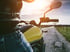Motorradfahrer auf einem gelben Motorrad auf einer Landstraße mit Sonnenlicht und blauem Himmel.