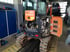 Hitachi Minibagger mit geöffneten Wartungsklappen steht zur Reparatur in einer Werkstatt auf einer Grube.