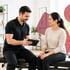 Male chiropractor explains TMJ treatment to a female patient.