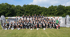 Große Gruppe von Kindern und Erwachsenen in schwarzen T-Shirts mit Fußbällen auf einem Sportplatz, Banner mit "TSA TORWARTCAMP".