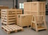 Verschiedene Exportverpackungen aus Holz, darunter Transportkisten, eine Europalette und ein A-Gestell in einer Lagerhalle.