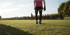 Fußballspieler in rosa Trikot und schwarzen Shorts steht auf grünem Rasen neben einem Fußball.