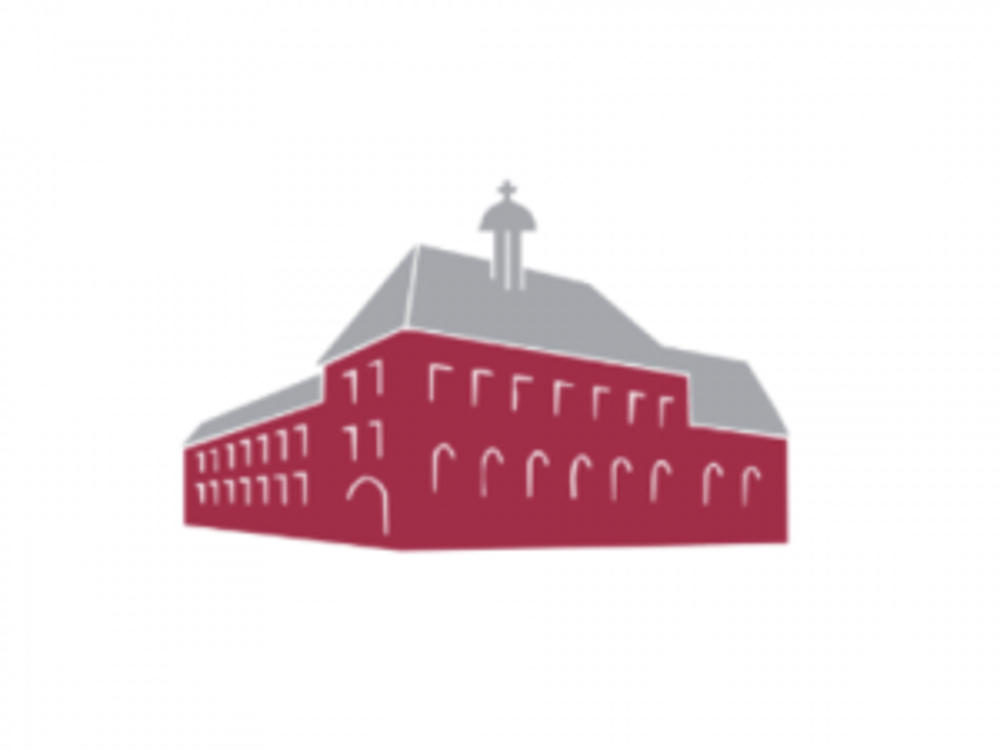 Grau-rotes Gebäude mit einem Turm in der Mitte und vielen Fenstern.
