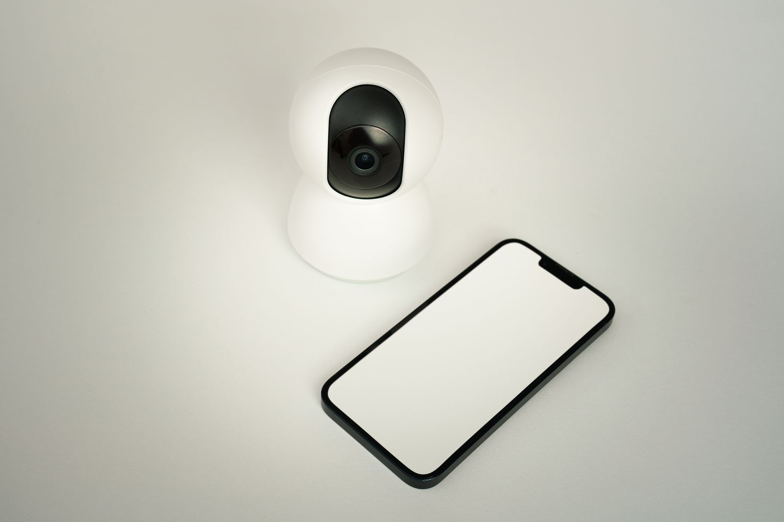 Security camera paired with a phone showing the monitoring app
