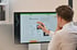 Mann mit Brille zeigt mit blauem Stift auf einen Computermonitor mit einer Webseite.