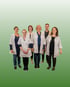 Team der Billroth Apotheke – sechs Mitarbeitende in weißen Kitteln und Freizeitkleidung vor grünem Hintergrund, kompetente Beratung und Arzneimittelservice.