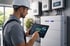 Techniker im Schutzhelm prüft Energieüberwachung auf einem Tablet neben Batterien und Wechselrichtern.