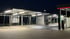 SB-Waschboxen und SB-Sauger mit blauen Schläuchen auf beleuchtetem Parkplatz bei Nacht.