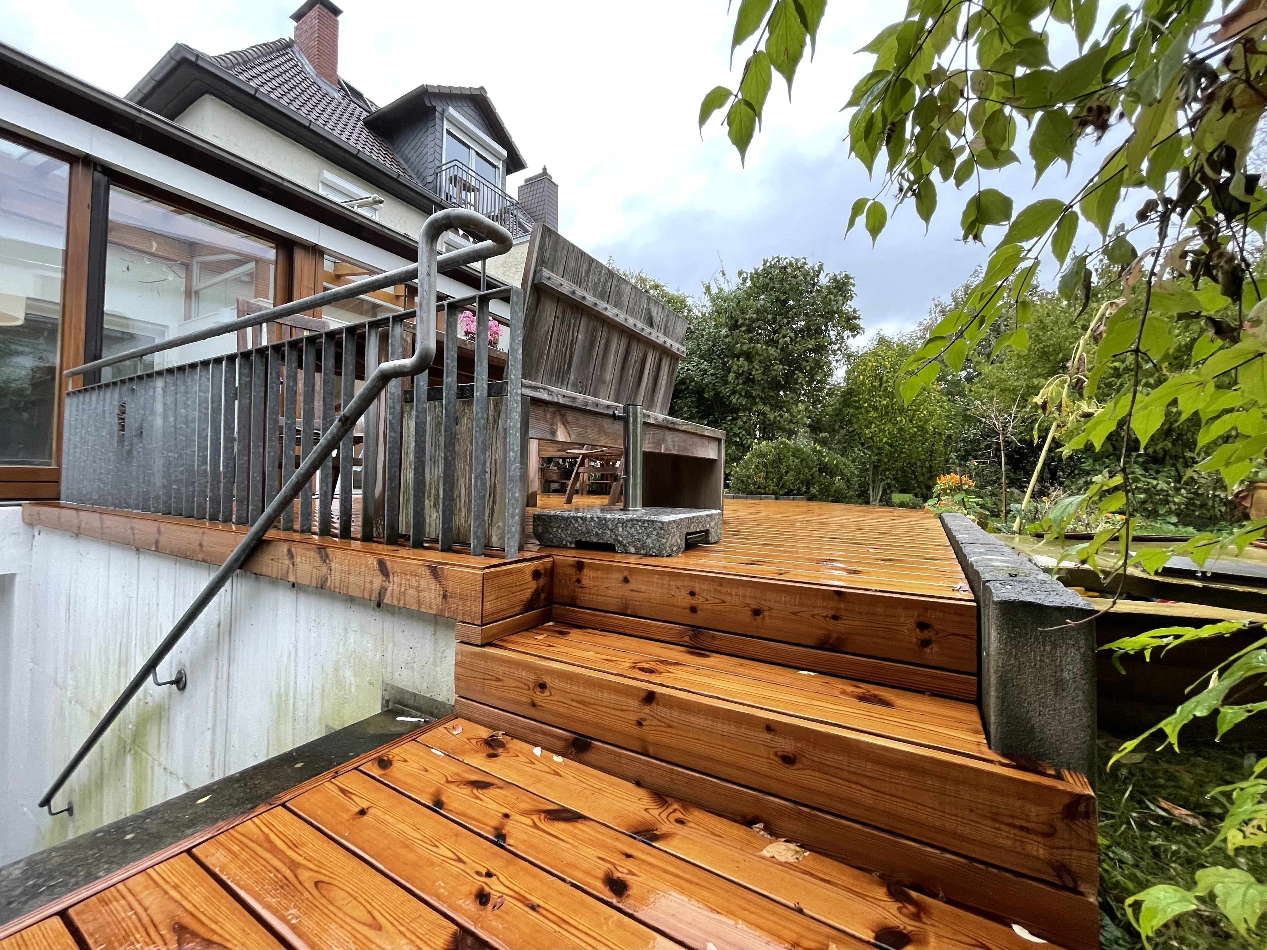 Holzterrasse aus Thermokiefer mit Stufen und angrenzendem Gartenbereich