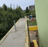 Frisch gegossener Betonbalkon mit grüner Hauswand und Baumlandschaft im Hintergrund.