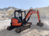Oranger Kubota Minibagger auf einer Baustelle, der Erde in einem Fundament aushebt.