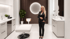 Blonde Frau in schwarzem Anzug steht in einem modernen, minimalistischen Behandlungsraum.