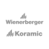 Grauer Text "Wienerberger Koramic" mit Dachziegel-Symbolen auf dunkelgrünem Hintergrund.