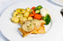 Gebratenes Fischfilet mit Zitronenscheiben, Petersilienkartoffeln, Brokkoli, Blumenkohl und Karotten auf weißem Teller.
