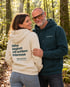 Paar im Wald, die Frau trägt einen cremefarbenen Wearmorrow® Hoodie mit der Rückenbotschaft Nähe beginnt mit echtem Interesse