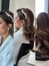 Eine Frau mit braunen welligen Haaren und einem geflochtenen Zopf trägt ein blattförmiges Haaraccessoire und lange Ohrringe.