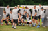 Eine Gruppe von Fußballspielern in grauen Trikots und schwarzen Shorts posiert auf einem Rasenplatz.