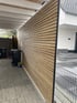 Ein Carport mit einer Sichtschutzwand aus waagerechten Holzlamellen neben einer gepflasterten Einfahrt.