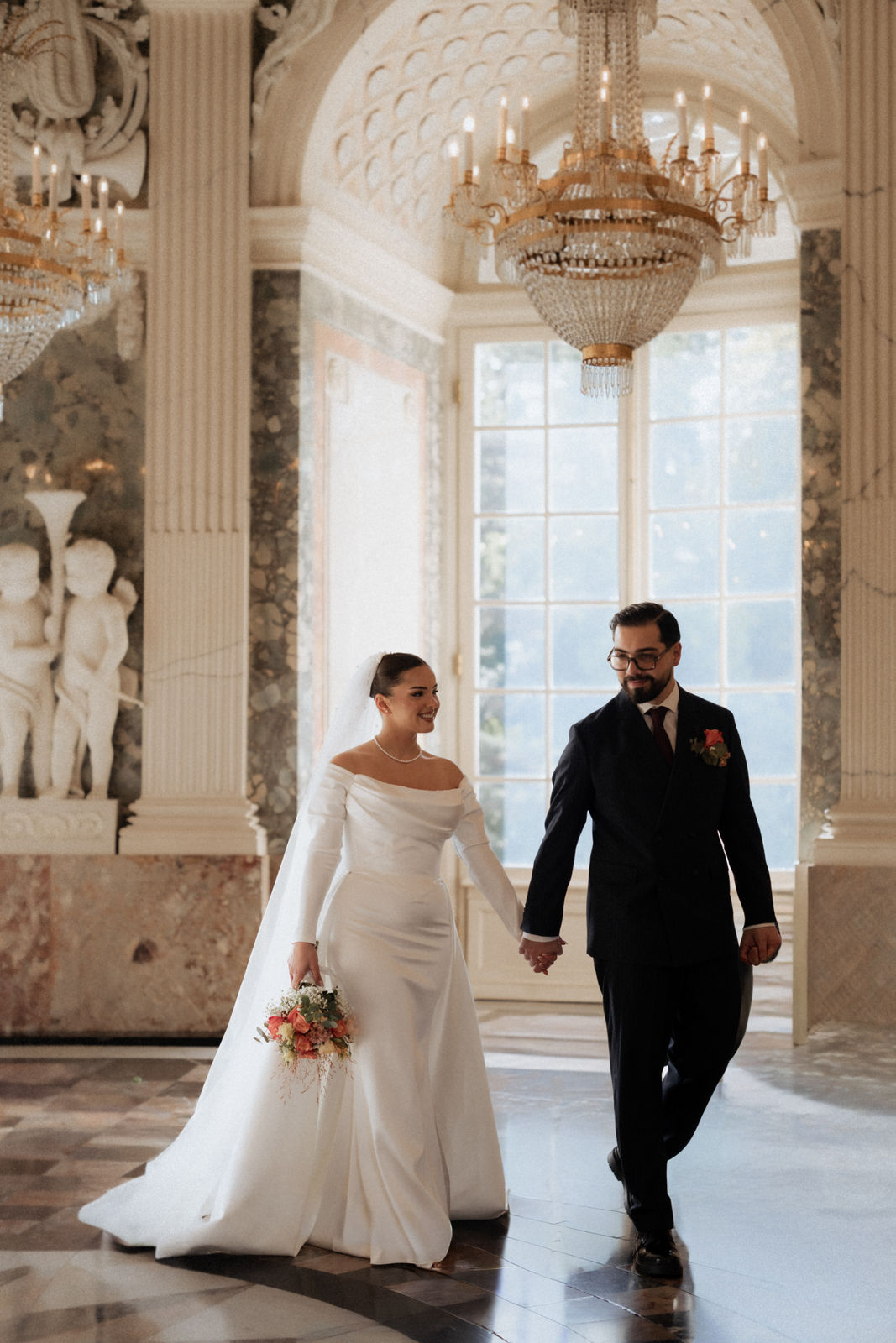 Brautpaar geht Hand in Hand durch den Festsaal von Schloss Benrath in Düsseldorf.
