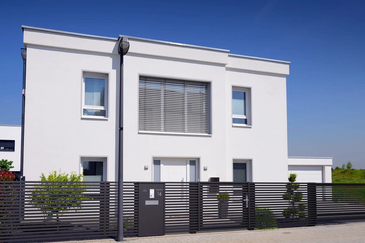 Modernes weisses Haus mit Flachdach und schwarzem GUARDI Aluzaun