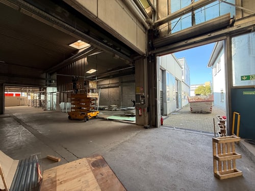 Geräumte Halle mit offenem Tor und Hebebühne