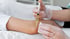 Person in gloves injects a syringe with liquid into a patient's elbow.