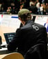 Eine Person mit Kappe und schwarzer Jacke mit "FD"-Logo arbeitet an einem Laptop am Spielfeldrand.