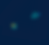 Zwei unscharfe, helle Lichtpunkte in Blau und Gelb auf dunklem marineblauem Hintergrund.
