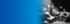 Eine Hand hält ein leuchtendes ISO 27001 Zertifizierungs-Icon vor blauem Hintergrund und IT-Sicherheitssymbolen.