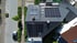 Draufsicht auf ein Haus mit Solarpaneelen auf dem Dach und einem grauen Auto auf der Straße.
