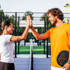 Zwei Padel-Spieler geben sich auf dem Platz ein High Five, der Mann hält einen schwarzen Schläger.