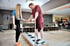 Ein Mann trainiert auf einer Balanceplatte, gestützt von einem Trainer