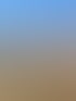 Geschichtete Felsformationen und Sträucher unter einem blauen Himmel mit weißen Wolken.