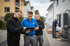 Drei Installateure überprüfen eine Wärmepumpeninstallation im Freien; einer zeigt auf ein Tablet.