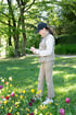 Eine Frau mit Kappe und Weste steht auf einer Wiese und macht sich Notizen auf einem Klemmbrett vor bunten Tulpen.