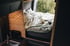 Gemütliches Bett im Campervan mit Tageslicht und Holzverkleidung – Schlafbereich im Reisewagen Sportive mit 196 cm Liegefläche