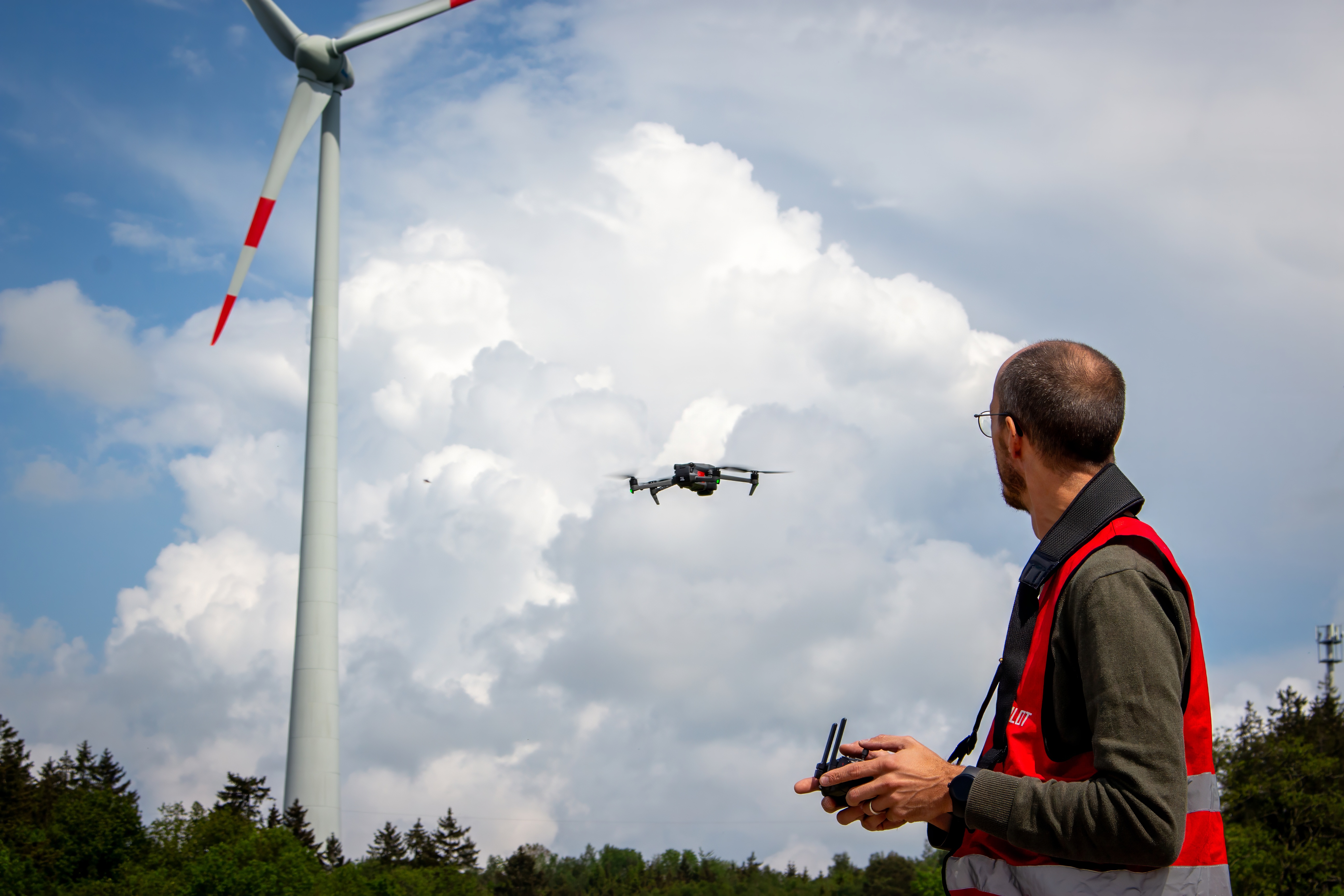 Drohne vor Windkraftanlage bei der Wartung