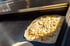 Fladenbrot mit geriebenem Käse auf einer Heizplatte.