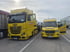 Gelber ADAC-LKW mit aufgeladenem Auto und gelber ADAC-Transporter mit offenen Türen auf Parkplatz.