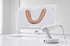 Ein Intraoralscanner steht neben einem Monitor, der ein digitales 3D-Modell eines menschlichen Zahnbogens zeigt.