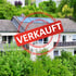 Haus mit Solarpaneelen und einem roten Stempel "VERKAUFT".