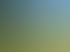 Ein grünes Klettergerüst und eine Wippe auf einer großen Wiese unter blauem Himmel.